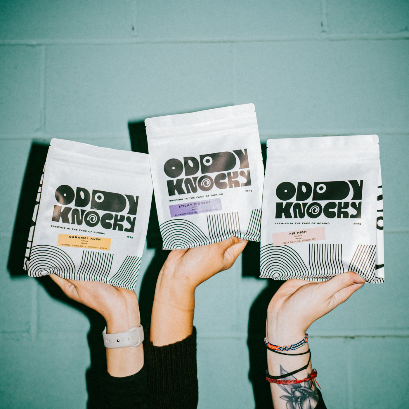3 bags of Oddy Knocky coffee held by hands, showcasing the Prepaid Coffee Subscription offerings.