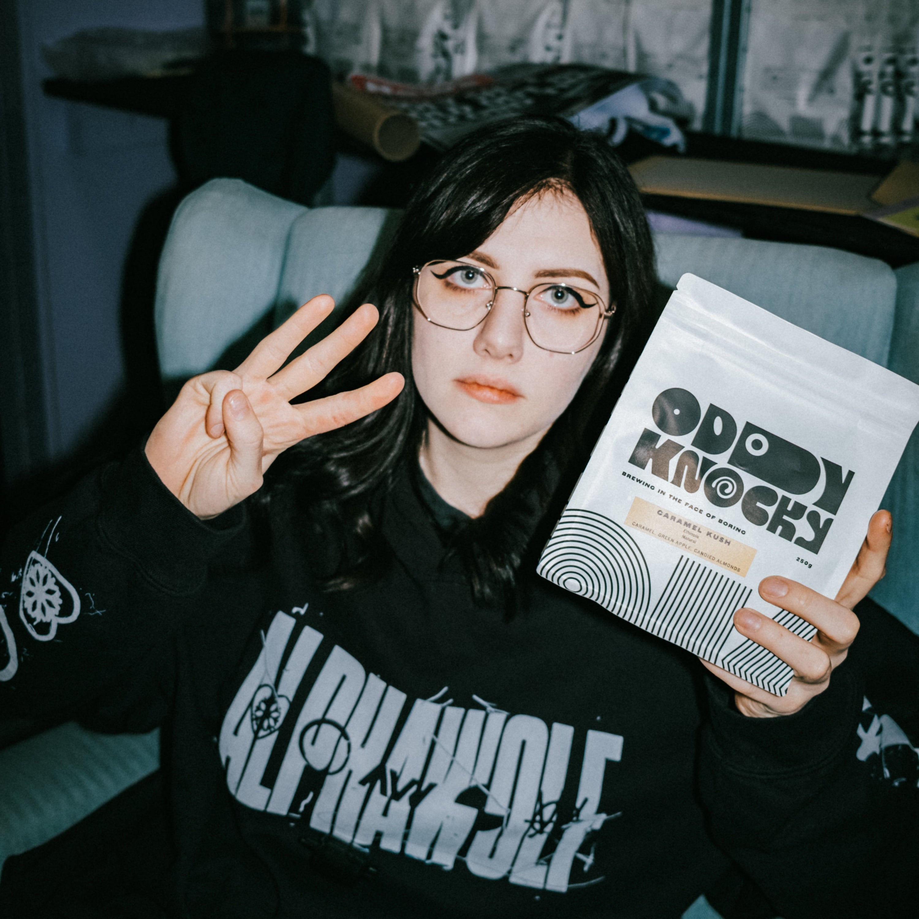 Person holding a bag of coffee, promoting the Prepaid Coffee Subscription while sitting on a chair.