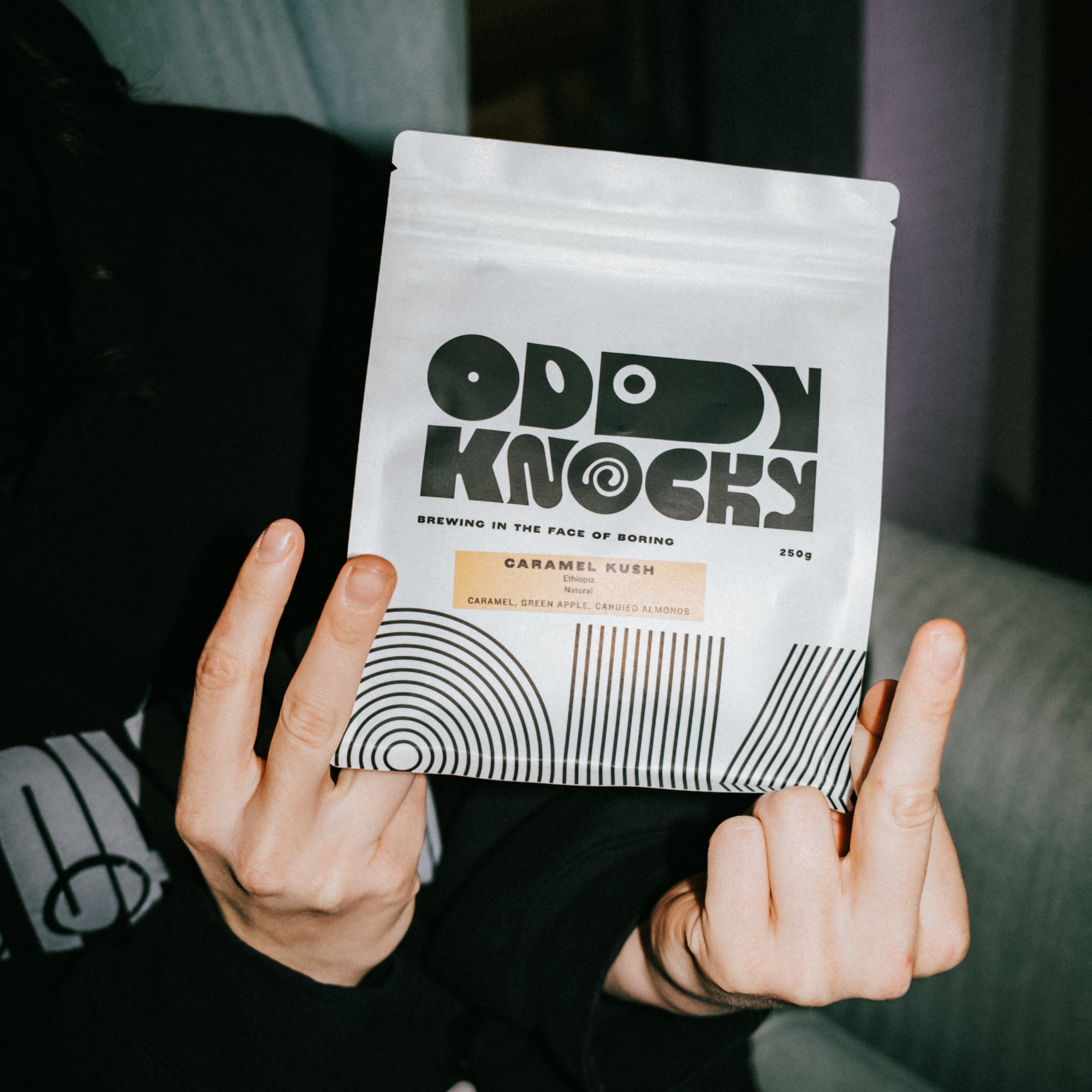 Person holding a bag of Caramel Kush coffee from Oddy Knocky, showcasing a prepaid coffee subscription.