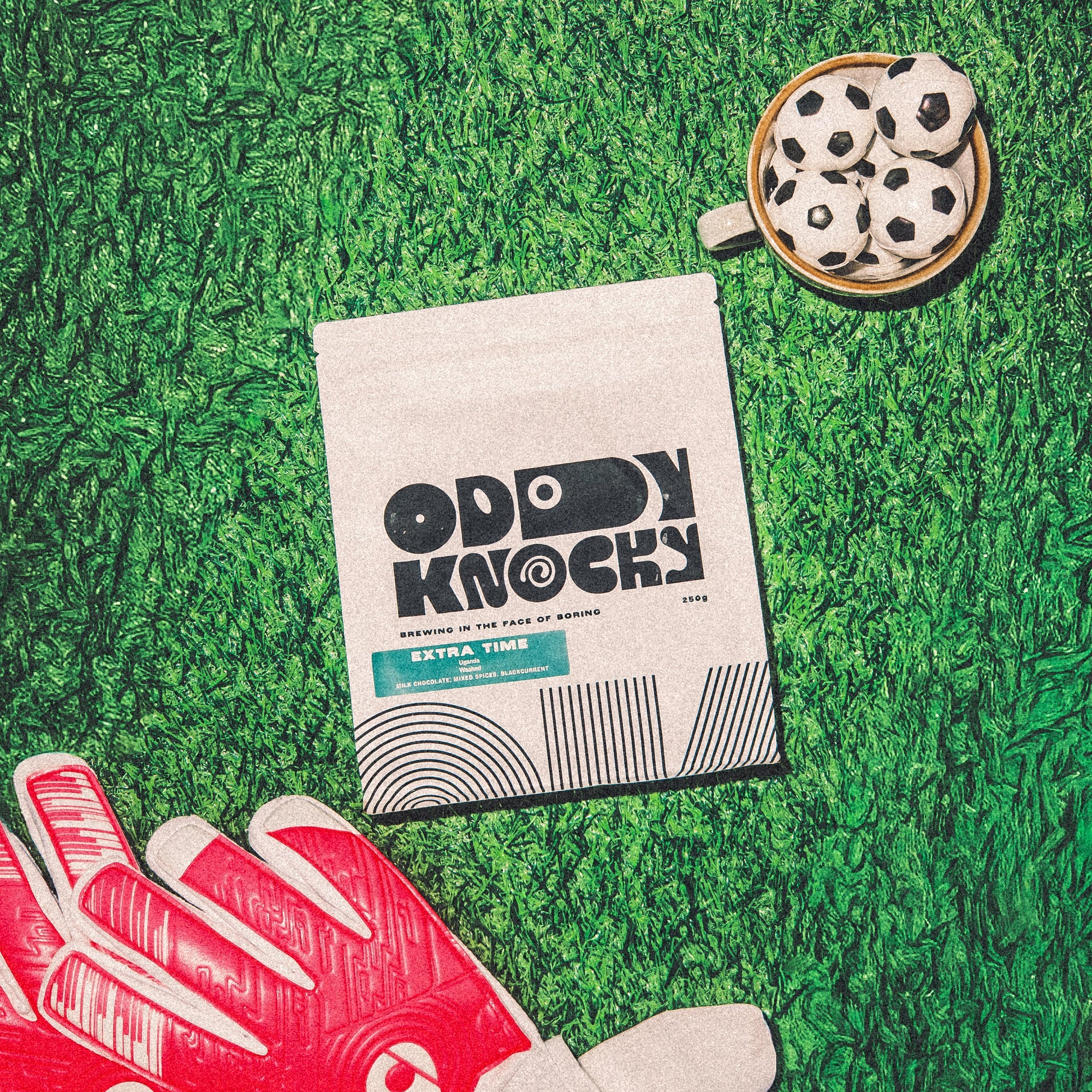 Extra Time Ugandan Coffee packaging on green grass with football-themed items.