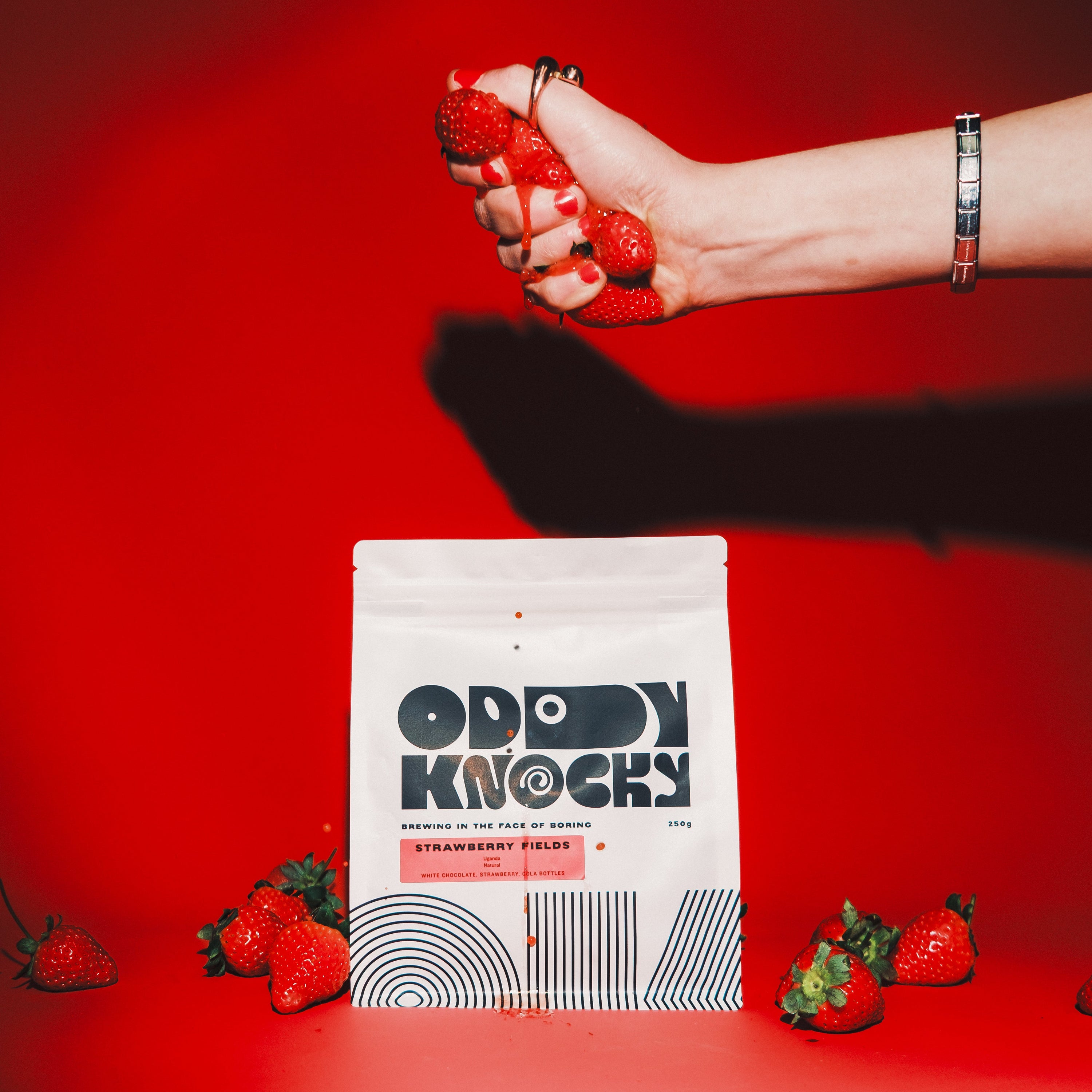Strawberry Fields coffee bag with fresh strawberries, showcasing Ugandan natural coffee flavors.