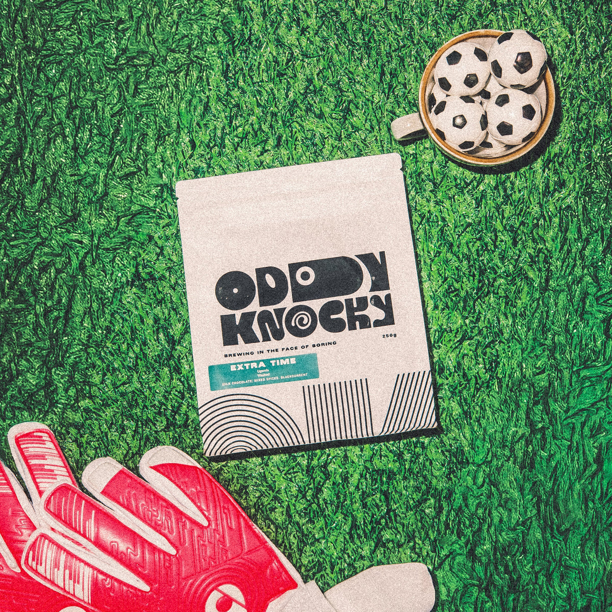 Extra Time Ugandan Coffee packaging on green grass with football-themed items.