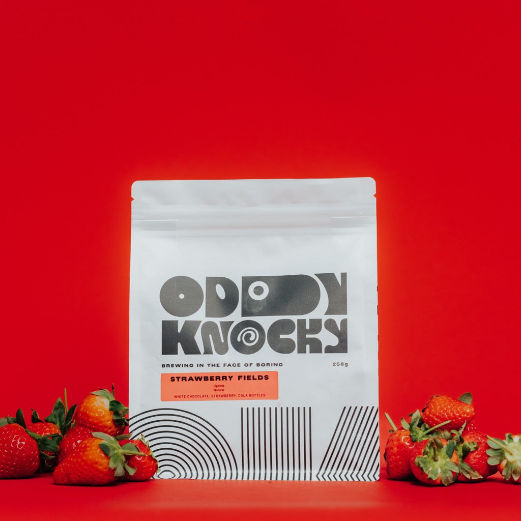 Strawberry Fields coffee bag with strawberries on red background, showcasing Ugandan natural coffee.